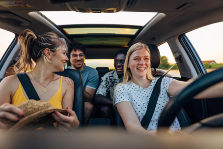 A lovely woman drives a car as she travels with a diverse group of friends on a summer vacation stock photo